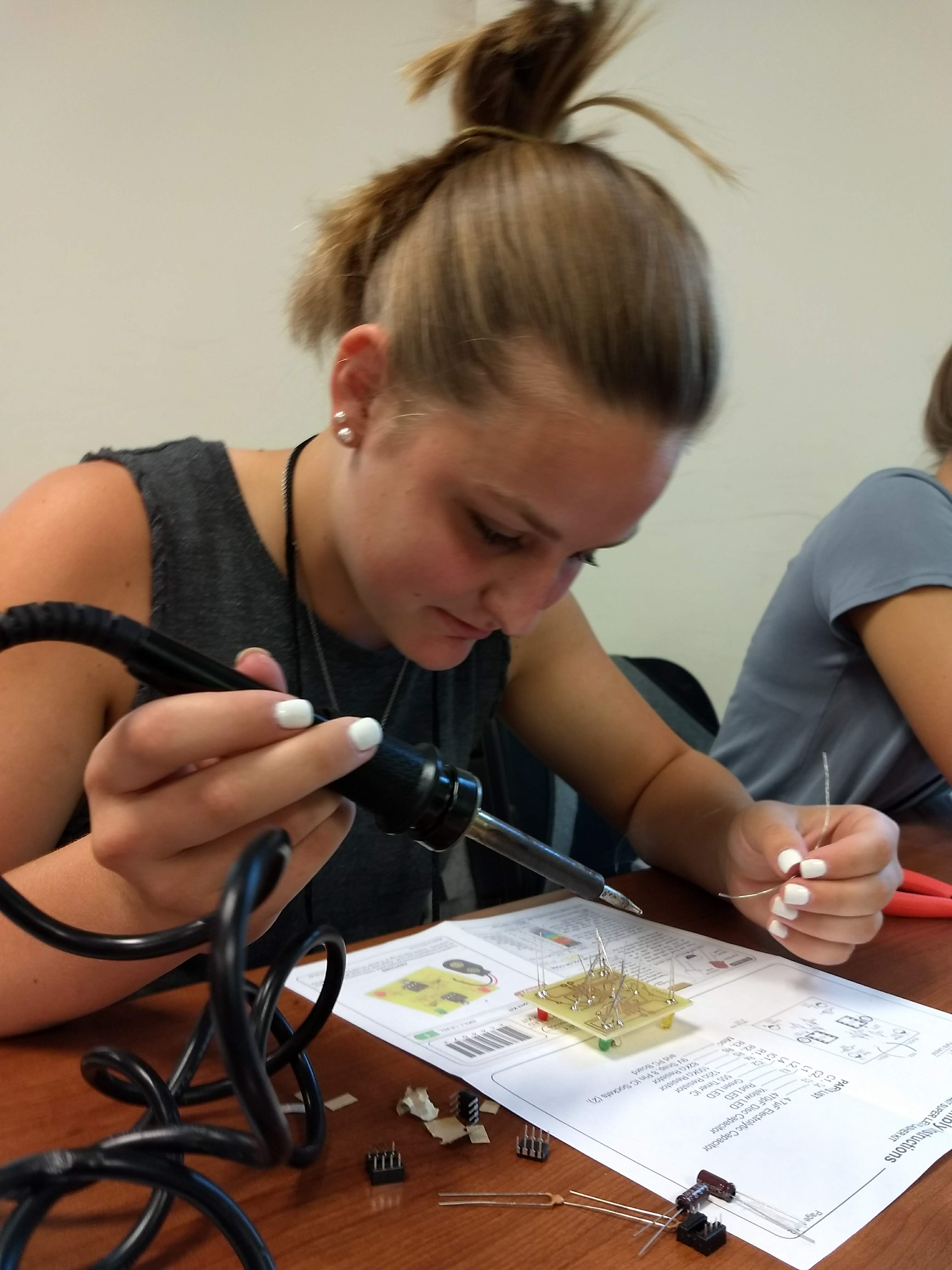 Grace Henderson soldering on her circuit board during one of the workshops at 4-H Electric Congress