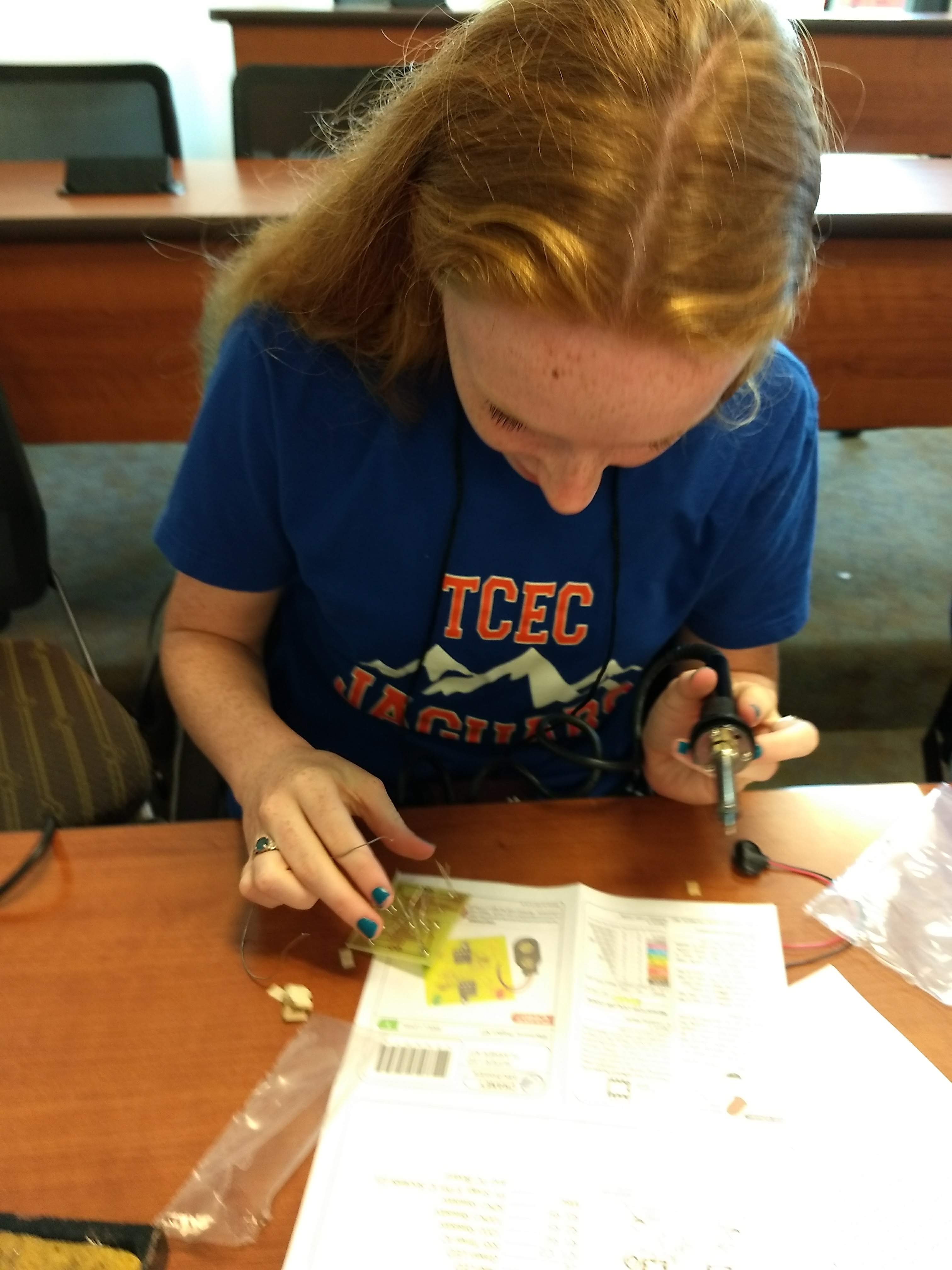 Hannah Smith studying her circuit board making sure everything is right before she solders