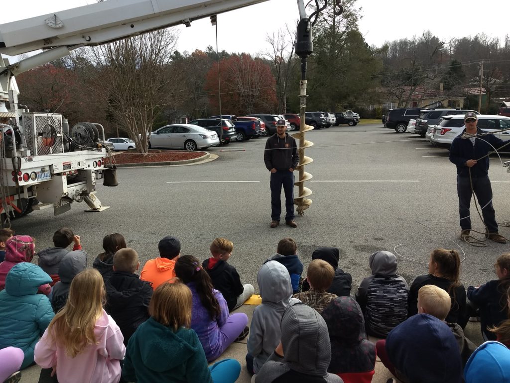 linemen teaching a group of children