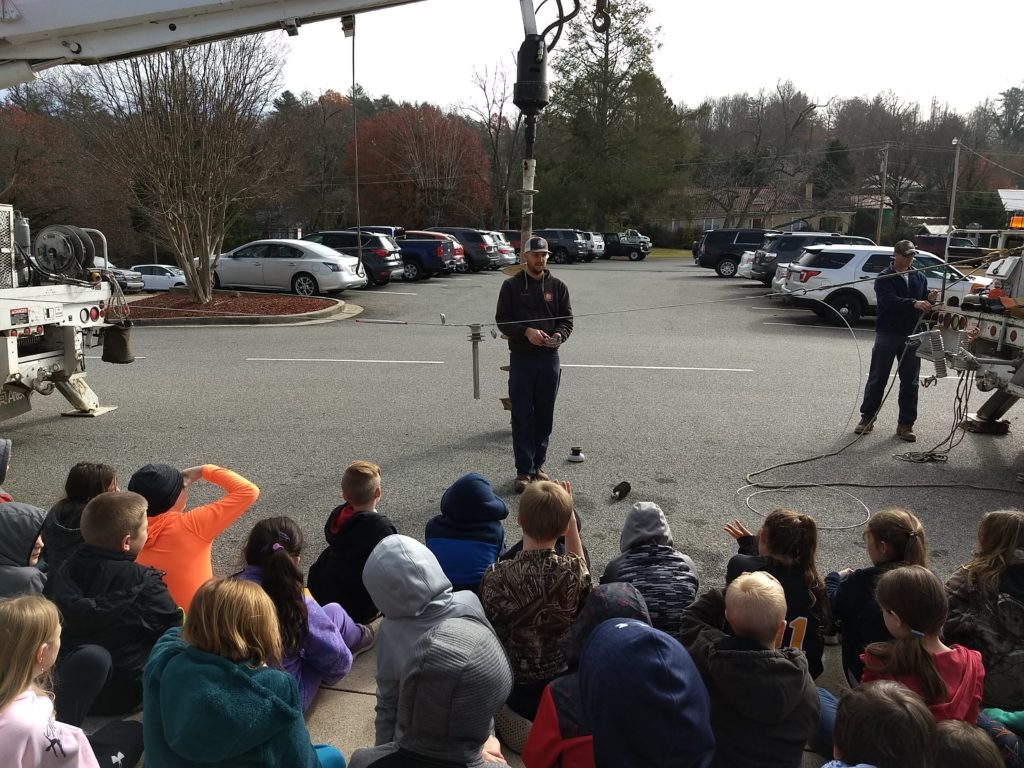 linemen teaching a group of children