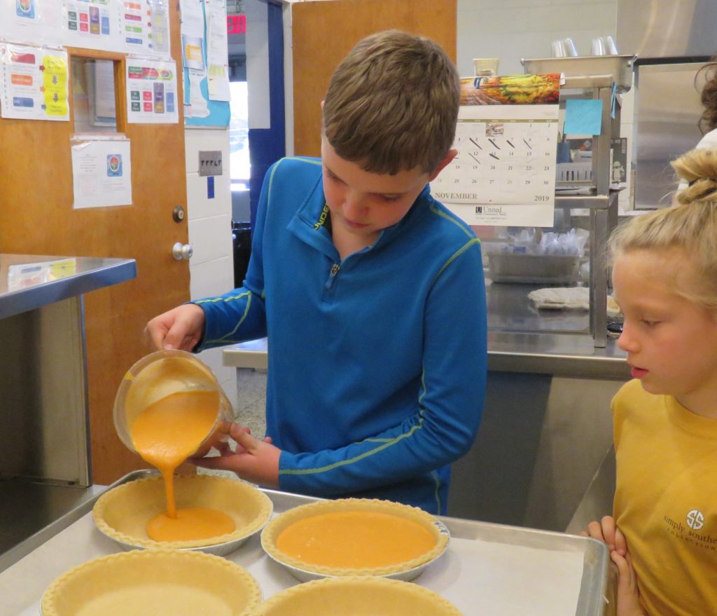 child pouring filling into pies