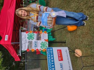 A girl poses with an award winning painted pumpkin.