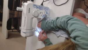 A girl sews with a machine at a table.