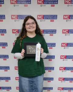 A girl poses with her ribbon winning project.