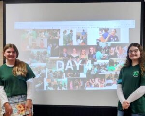 Two girls pose with a presentation.