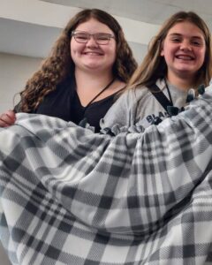 Two girls display a sewing project.